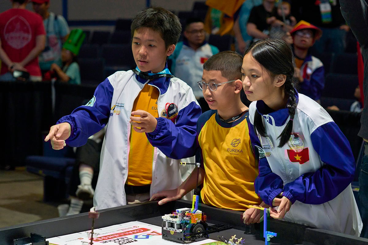 Three FIRST LEGO League students cheering on their robot at FIRST Championship.