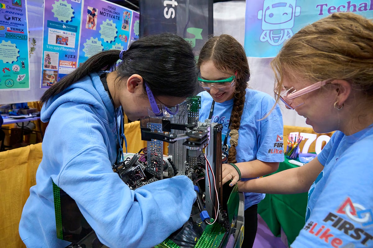 Three FIRST Tech Challenge students working on their robot at FIRST Championship