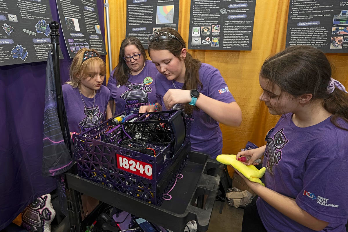 FIRST Tech Challenge students working on robots in pits at 2026 FIRST Championship with the help of a mentor