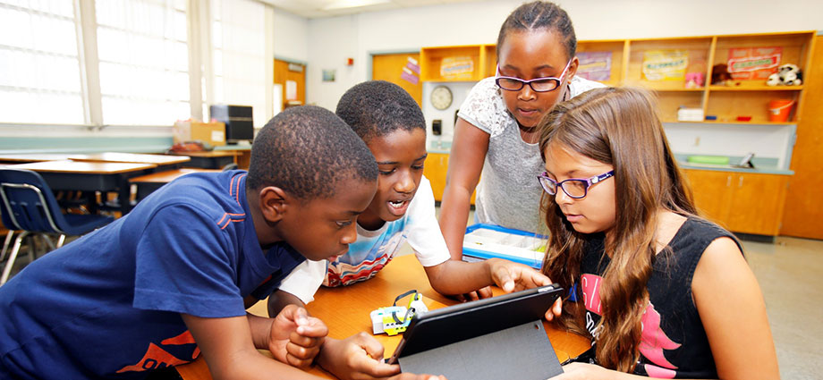 Students program a LEGO robotics model.