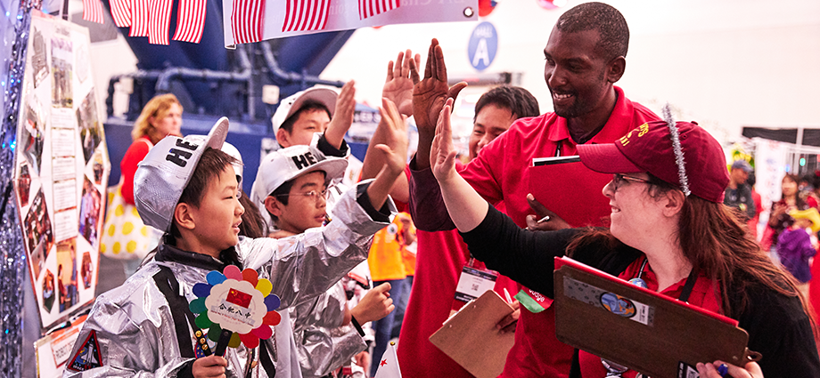 FIRST students give high-fives to judges at a robotics event